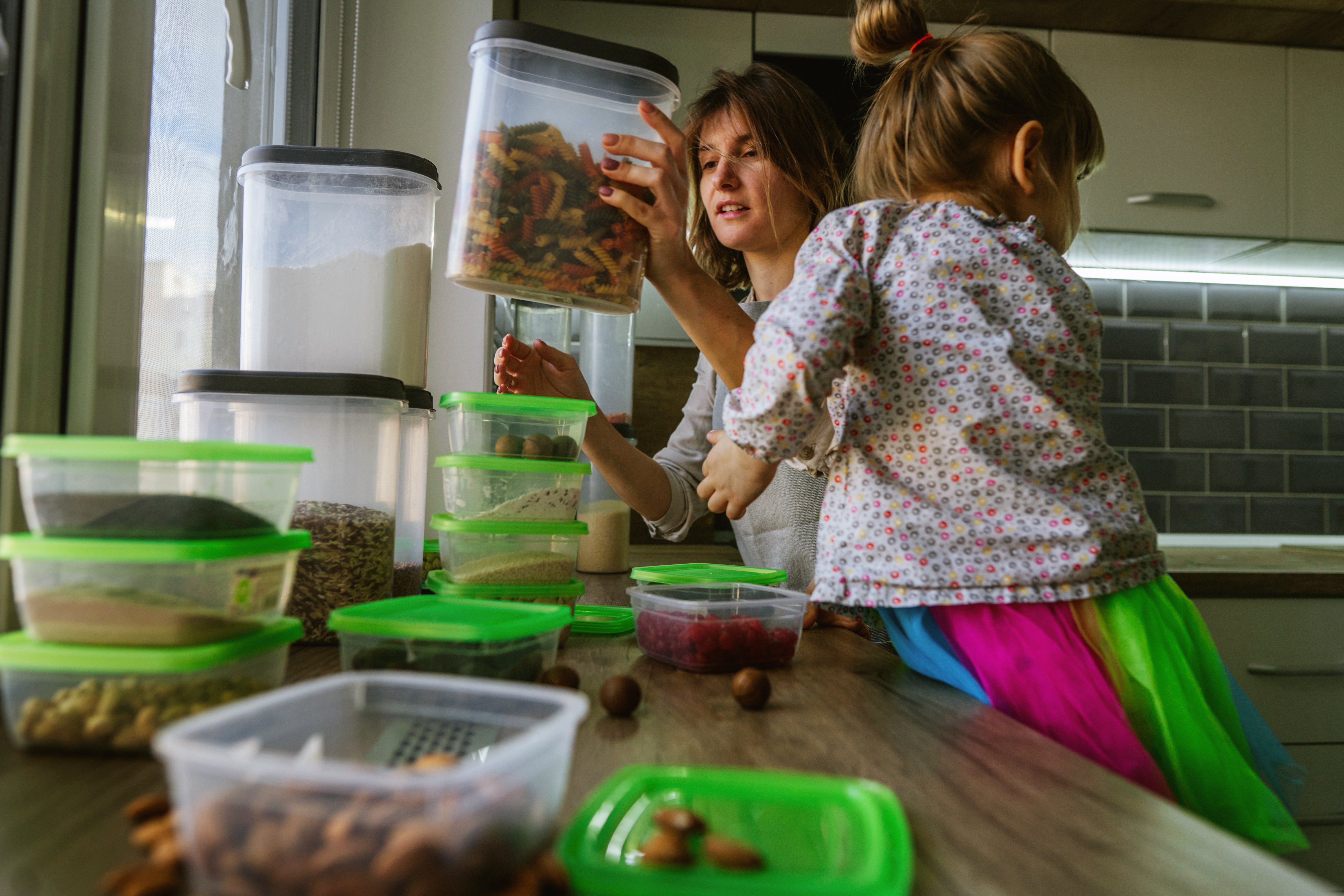 mom-and-her-little-daughter-filling-food-container-2022-11-07-10-15-18-utc