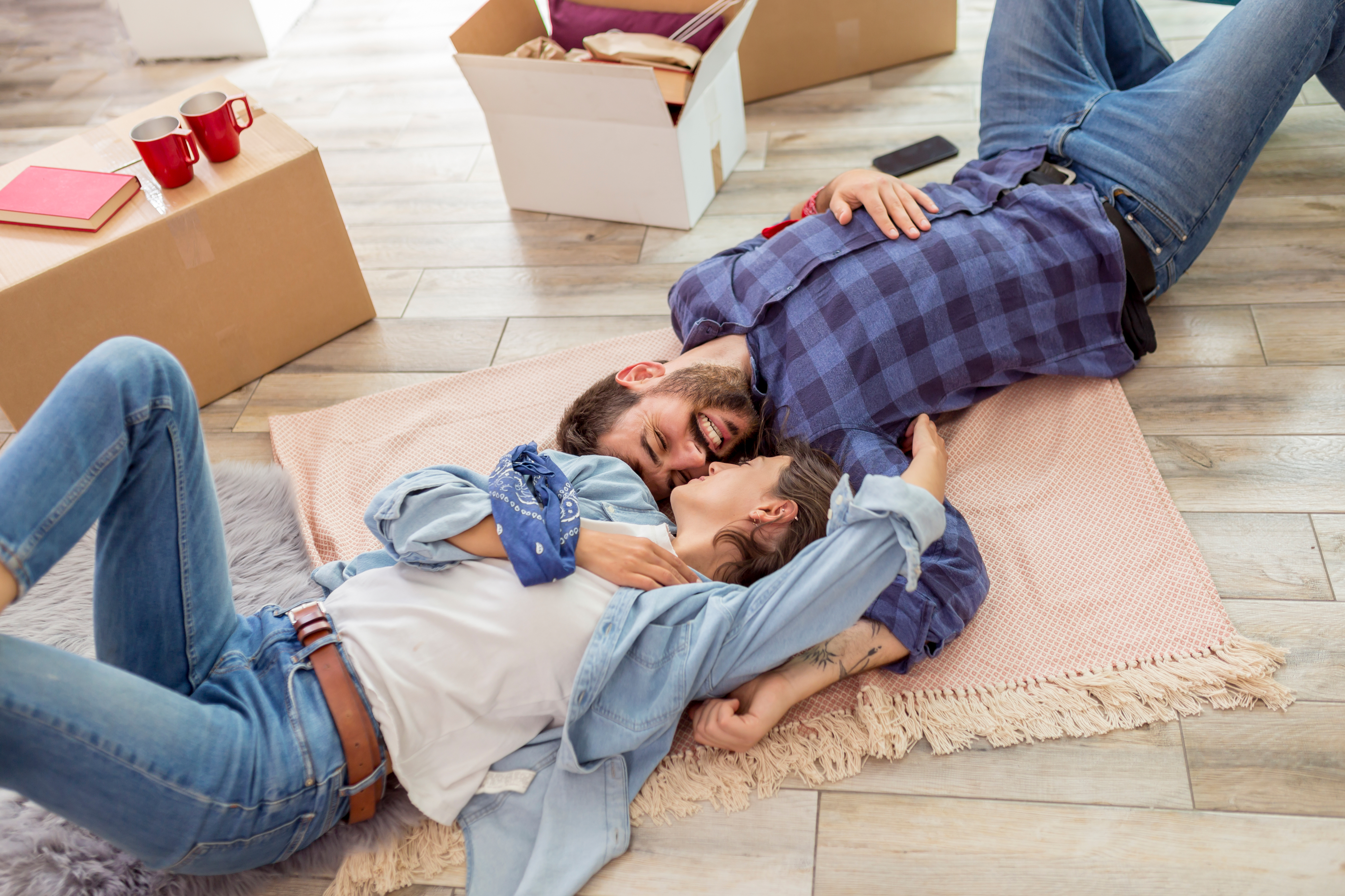 Couple laying on the floor surrounded by boxes.