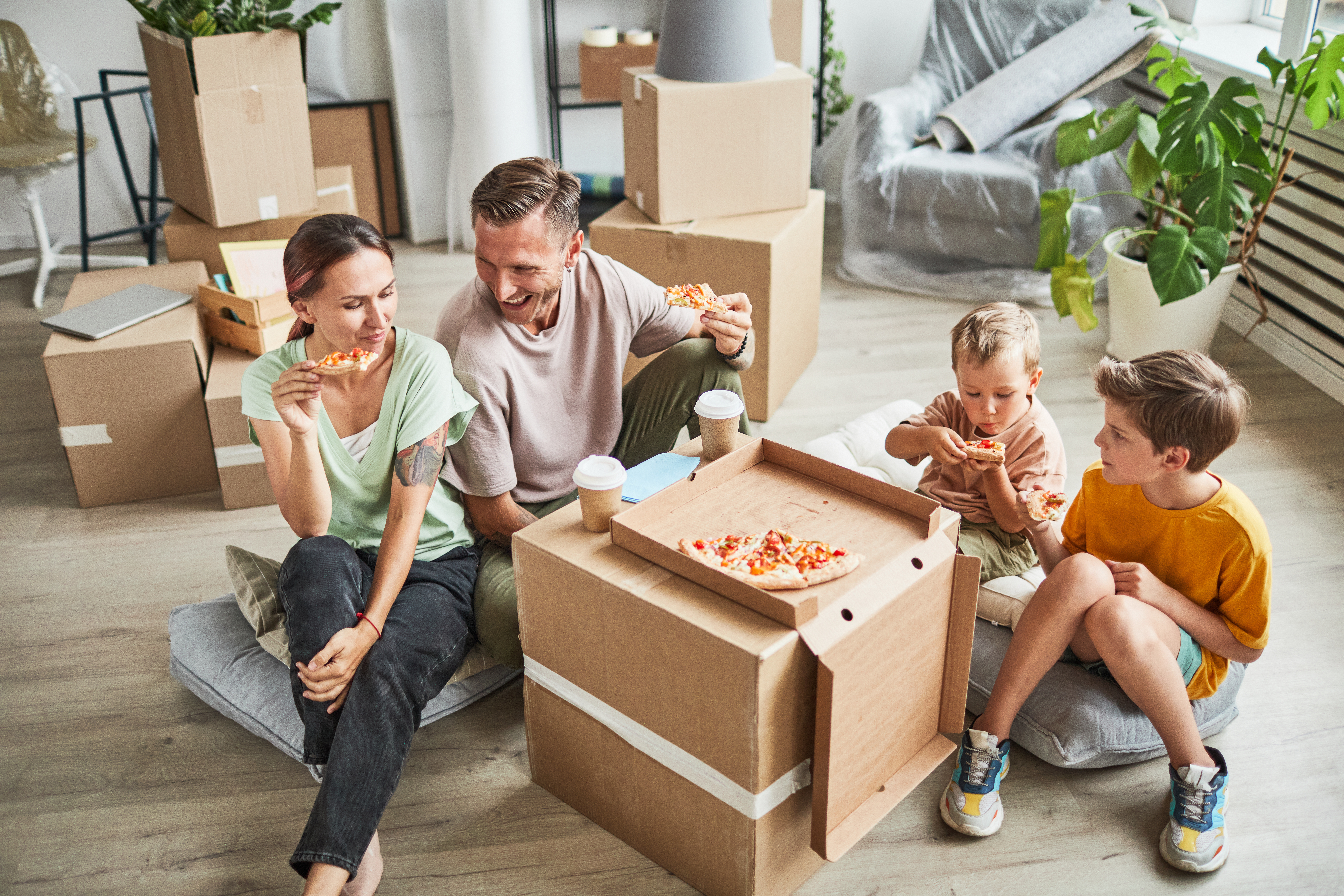 Family eating pizza off of a box while moving in to their new home.