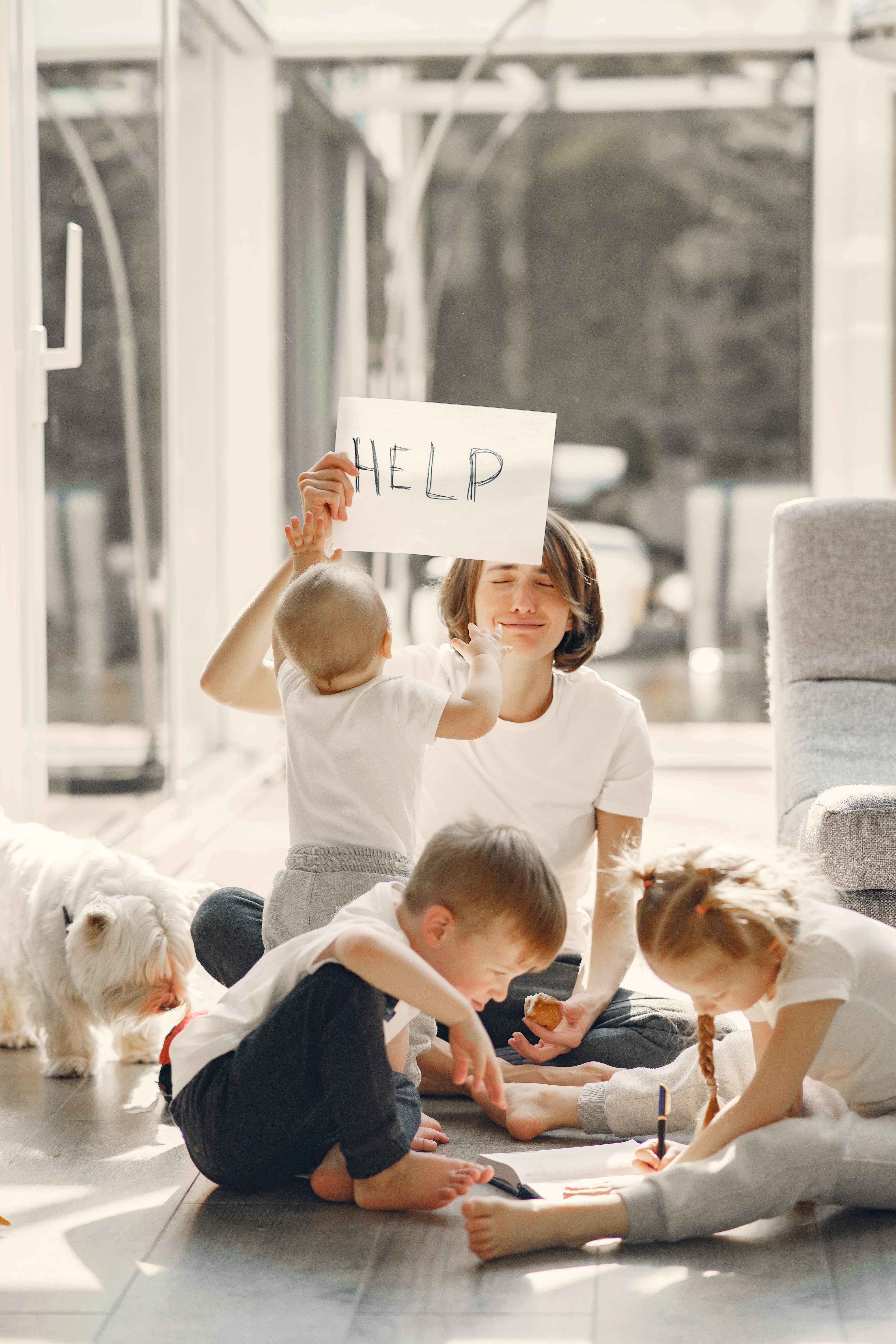 Mother with three children and dog holding up a HELP sign.